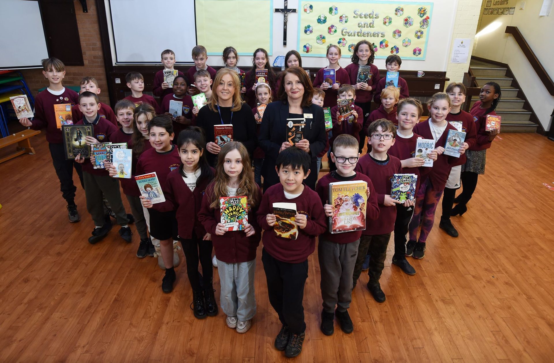 Children from St John the Evangelist RC Primary School standing up and holding their reading books for Wold Book Day